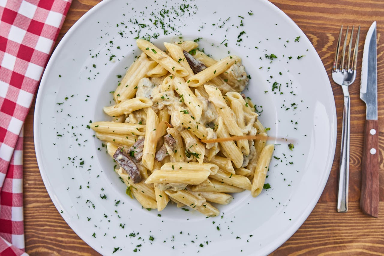 journey Delicious creamy penne pasta with mushrooms and parsley on a rustic table setting.
